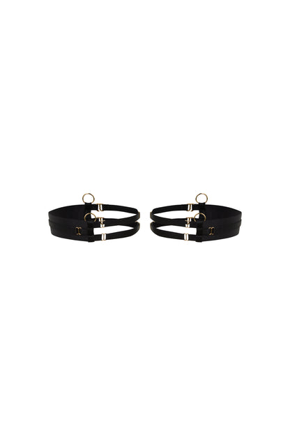 Kate black thigh garters with wide bands, slim adjustable straps and gold-tone hardware on a white background.