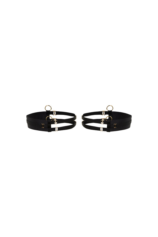 Kate black thigh garters with wide bands, slim adjustable straps and gold-tone hardware on a white background.